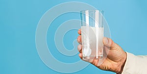 Close up of man holding a pill. Glass of water tablet. Glass with efervescent tablet in water with bubbles