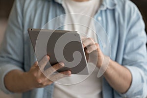 Close up man holding tablet, typing on screen, browsing apps