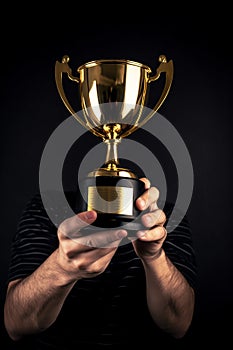 A close-up of A man holding up a gold trophy cup as a winner in a competition AI generated