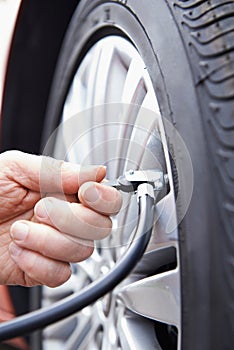 Close Up Of Man Inflating Car Tyre With Air Pressure Line