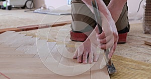 Close up of man installing wood flooring. Construction in a renovated room installation of parquet