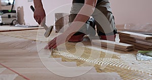 Close up of man installing wood flooring. Construction in a renovated room installation of parquet