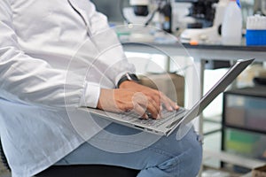 Close-up of man in Lab Coat Using Laptop Computer in Lab