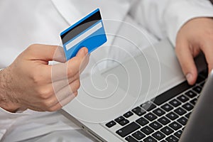 Close up of man with laptop computer and credit card at home