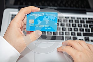Close up of man with laptop computer and credit card at home.
