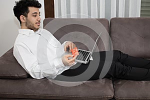 Close up of man with laptop computer and credit card at home.