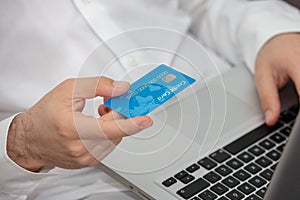 Close up of man with laptop computer and credit card at home.