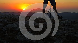 Close up man legs walk with trekking poles, climb on rock mountain hike travel on sunset. Spbd feet of tourist