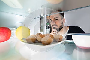 Close-up Of A Man Looking At Food Kept In Refrigerator