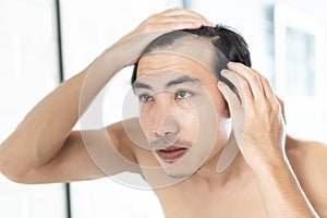 Close up man looking reflection in the mirror serious hair loss problem for health care shampoo and beauty product concept