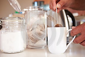 Close Up Of Man Making Tea In Cup Using Teabag