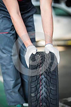 Close up of man mechanic carrying a tire in tire service