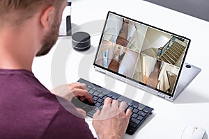 Businessman checking CCTV camera footage on laptop