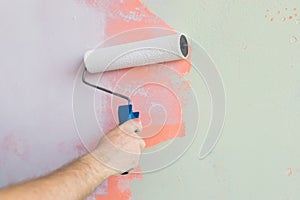 Close up man painting wall with paint roller - renovation and redecoration concept