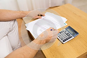 Close up of man with papers and calculator at home