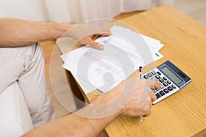 Close up of man with papers and calculator at home