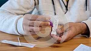 Close-up of man placing sample into a buffer dropper for seft detection of virus