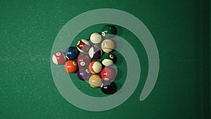 Close up man with plastic triangle rack with billiard balls on green table indoors