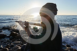 Close up man playing on bansuri traditional Indian instrument at sunrise seaside.