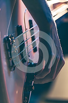 Close-up of a man playing the bass guitar.