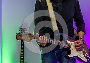 Close up of a man playing an electric guitar at home