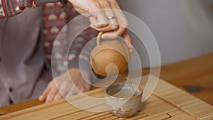 Close-up of man pouring Chinese tea. Art. Traditional Chinese tea with small teapot on wooden tray. Tea ceremony for one