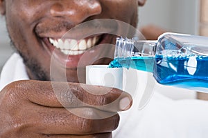 Close-up Of A Man Pouring Mouthwash Into Cap