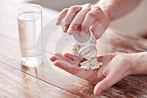 Close up of man pouring pills from jar to hand