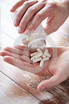 Close up of man pouring pills from jar to hand