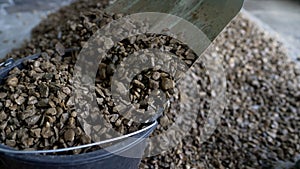 Close-up of a man pouring rubble. Sale of crushed stone. Crushed stone is poured into a bucket.