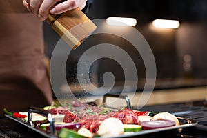 Close-up Man preparing Raw Steak Meat before Cooking seasoning with Sea Salt, Cooking Steak at Home in Modern Kitchen.