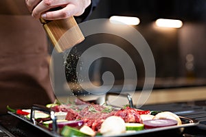 Close-up Man preparing Raw Steak Meat before Cooking seasoning with Sea Salt, Cooking Steak at Home in Modern Kitchen.