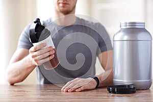 Close up of man with protein shake bottle and jar