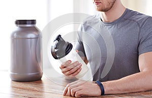 Close up of man with protein shake bottle and jar