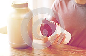 Close up of man with protein shake bottle and jar