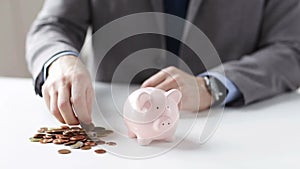 Close up of man putting coins into piggy bank