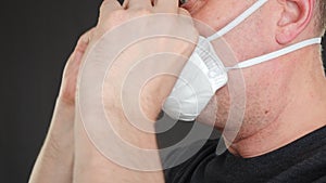 Close up man putting on facial mask for breath safety. Male face with respiratory mask on face while epidemic