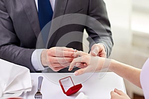 Close up of man putting ring to his fiance finger