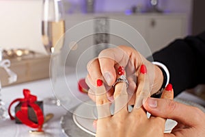 Close up of man putting ring to his woman finger.