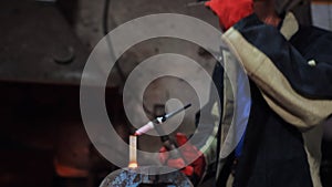 Close-up of a man in red gloves and a welding mask working with argon welding in a workshop.