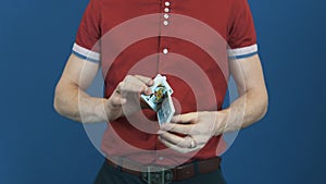 Close up man in red shirt on red back ground showing playing card shuffle trick