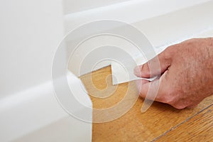 Close Up Of Man Removing Masking Tape From Skirting Board