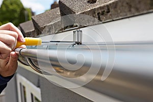 Close Up Of Man Replacing Guttering On Exterior Of House photo