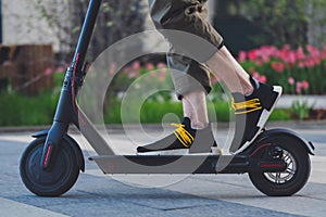Close up of man riding black electric kick scooter at beautiful park landscape
