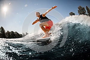 Close-up of man riding down the wave on surf style wakeboard on sunny day