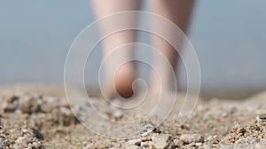 Close-up of a man`s feet on the beach, going into the water. Back view