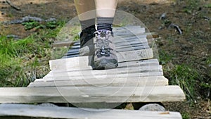 Close-up of a man`s feet walking on a flimsy wooden bridge