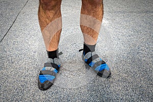 Close up of man& x27;s feet wearing indoor climbing wall shoes standing on soft flooring safety mat.