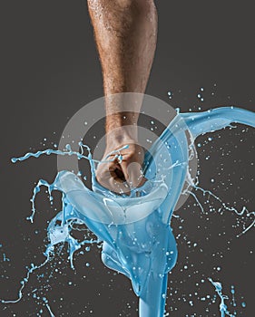 Close-up of a man's fist punching through liquid