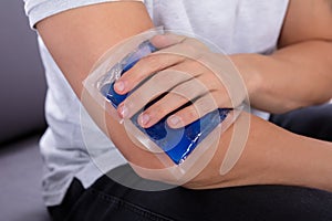 Man Applying Ice Gel Pack On An Injured Elbow photo